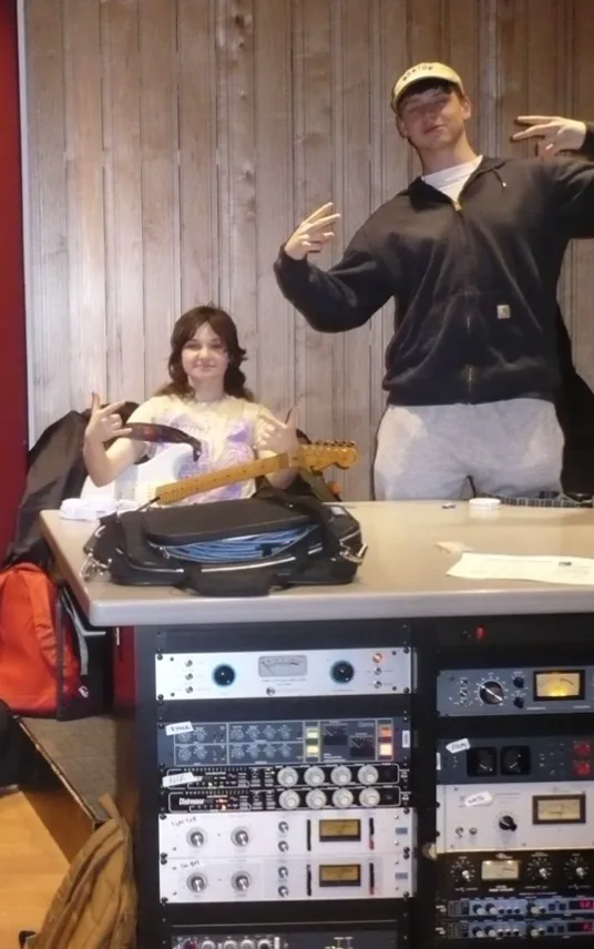Two members of Road Head From God in a studio, behind a desk of outboard gear